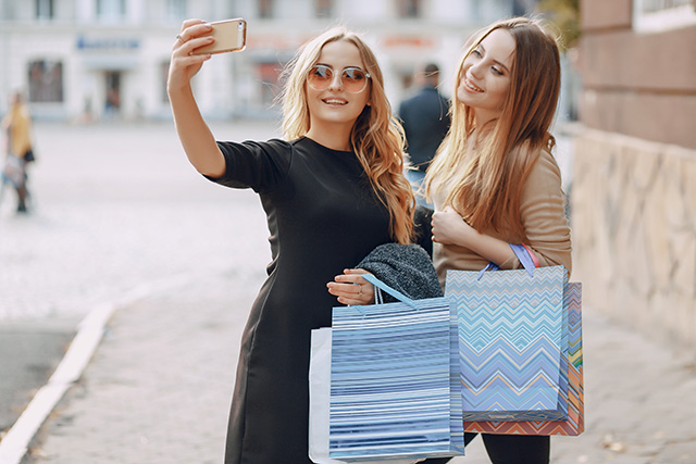 Deux amies prennent un selfie avec des sacs de shopping après leurs achats du Black Friday